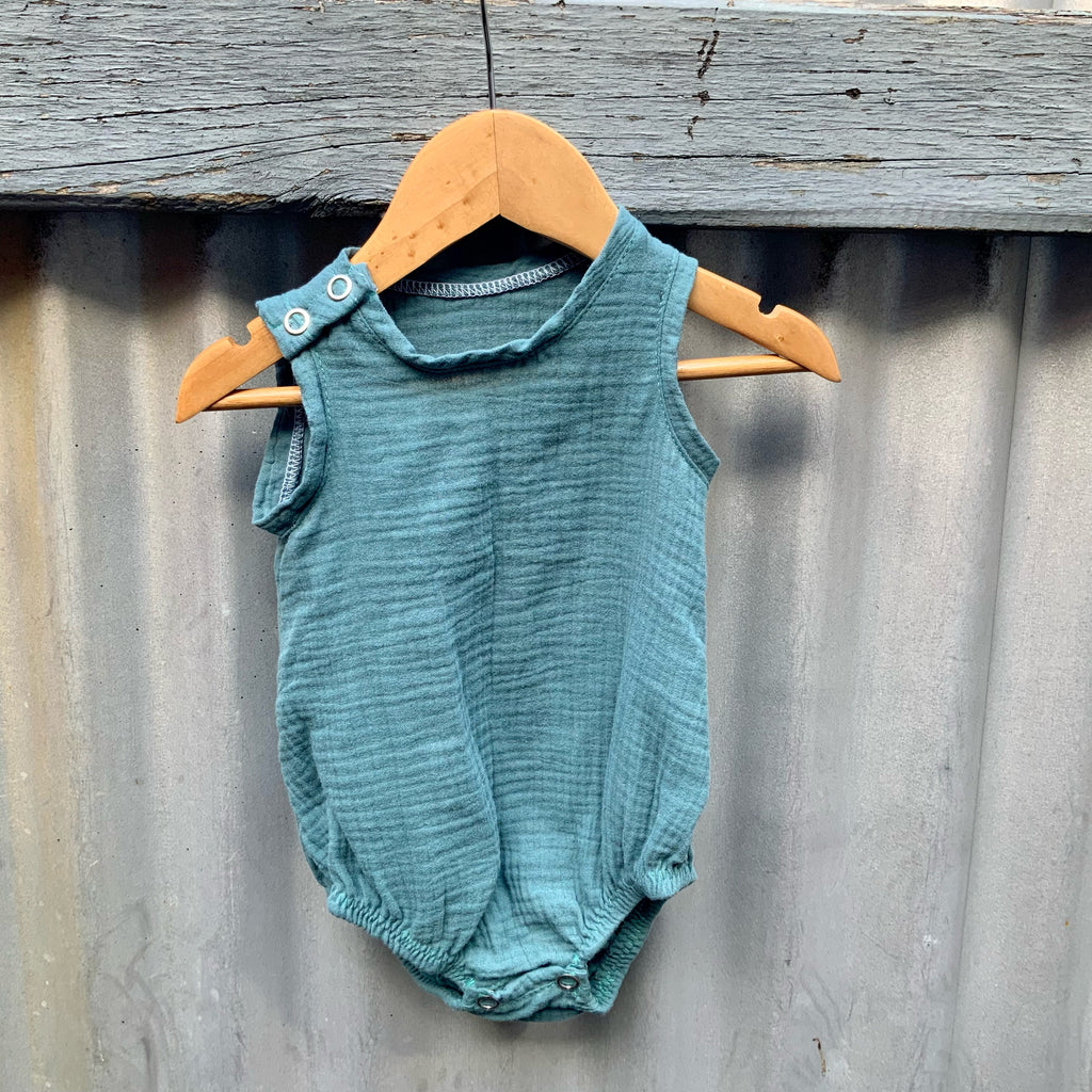 Blue Green cotton Baby Onesie hanging on a fence. Made in Australia by Asiki.