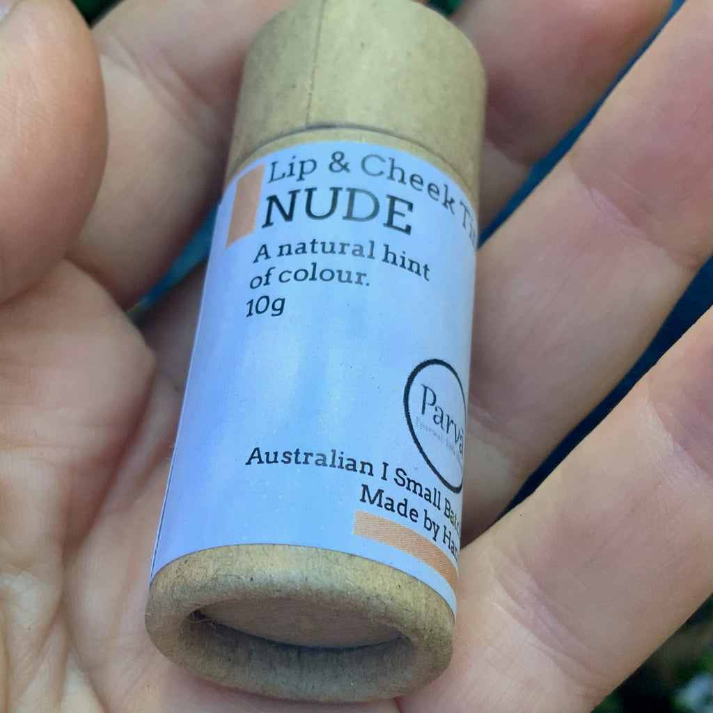 A photo of a hand holding a little cardboard tube of Nude Lip & Cheek tinted balm by Kirsty Mootz of Parva Little Things organic skincare. Available at Asiki.