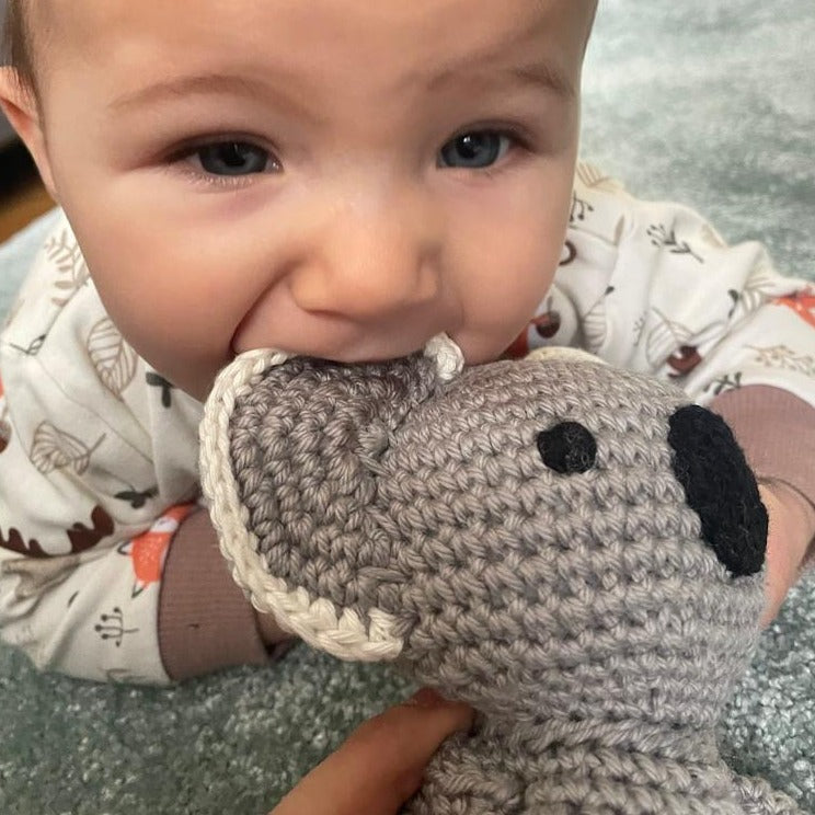 Baby chewing on a crochet koala eco toy