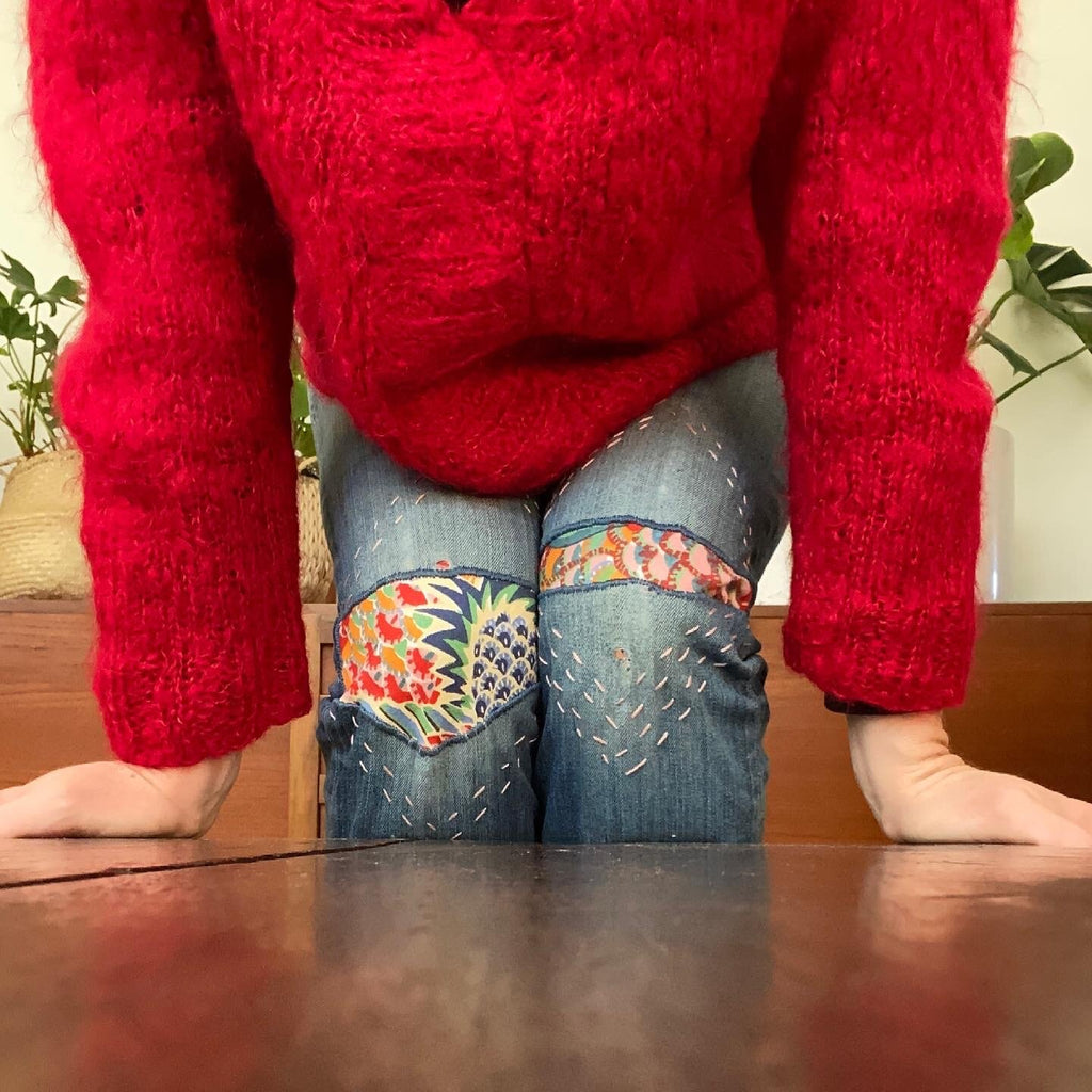 Photo of woman wearing red jumper and blue denim jeans that have been mended using the Visible Mending Kits from Asiki, Sydney, Australia.