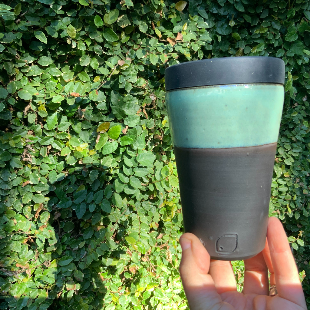 ceramic coffee cup with lid with light green glaze on black clay
