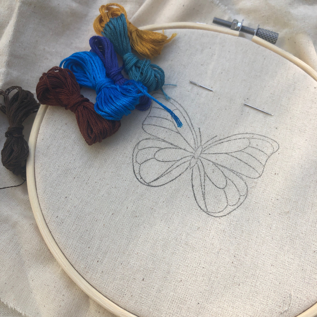 Photo of a Visible Mending Embroidery Kit from Asiki Sydney containing a hoop, cloth with butterfly motive, needle and several colourful embroidery threads. 