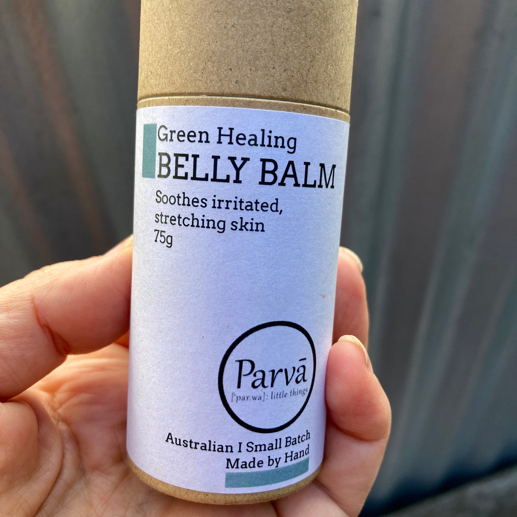 A hand holding a cardboard tube of Green Healing Belly Balm by Kirsty Mootz from Parva Skincare. Available at Asiki. 